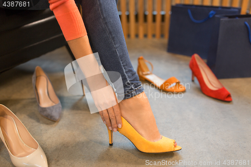 Image of young woman trying high-heeled shoes at store