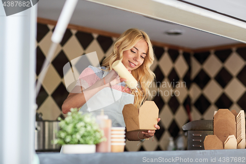 Image of happy saleswoman making wok at food truck