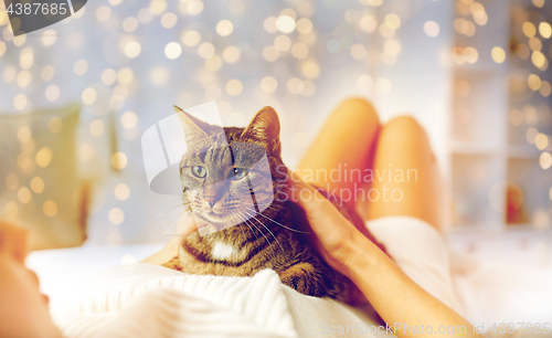 Image of happy young woman with cat lying in bed at home