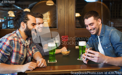 Image of friends with smartphone drinking green beer at pub