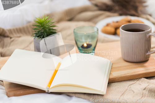 Image of diary, tea and candle in holder at home