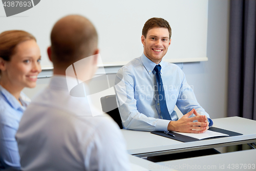 Image of happy coworkers meeting and talking at office