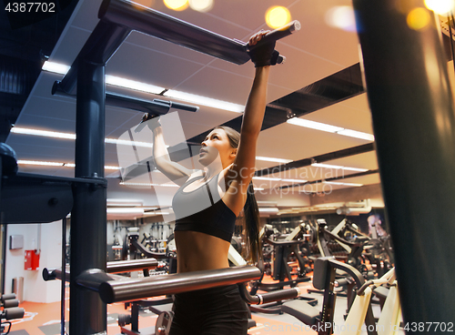 Image of woman exercising and doing pull-ups in gym