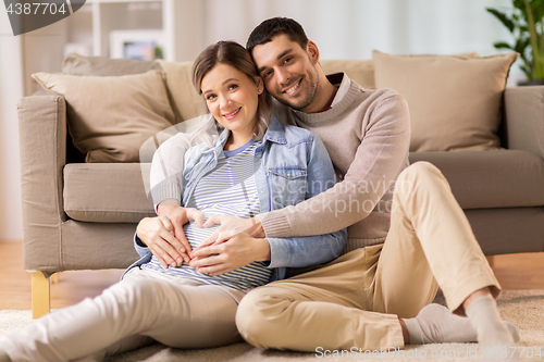 Image of man with pregnant woman making hand heart at home