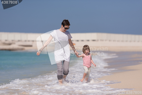 Image of mother and daughter running on the beach