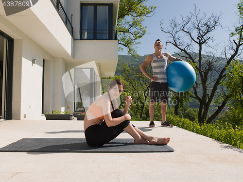 Image of woman and personal trainer doing exercise with pilates ball