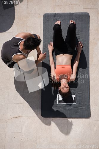 Image of woman with personal trainer doing morning yoga exercises top vie