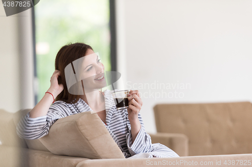 Image of young woman in a bathrobe enjoying morning coffee