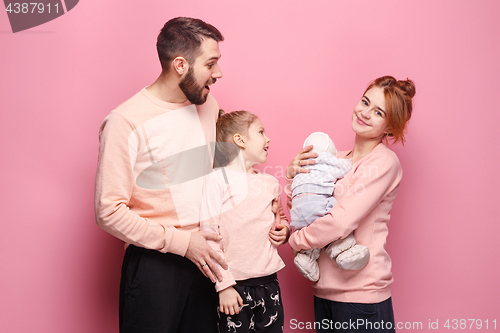 Image of Surprised young family looking at camera on pink