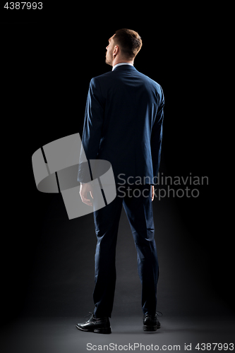 Image of businessman in suit over black