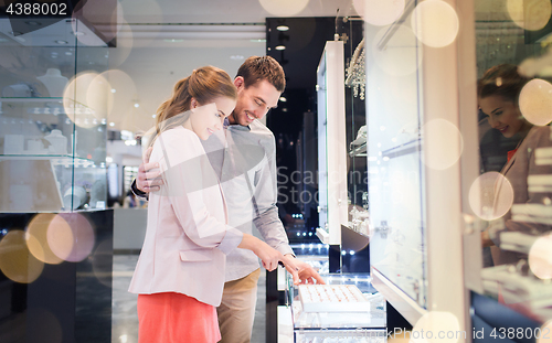 Image of happy couple choosing engagement ring in mall