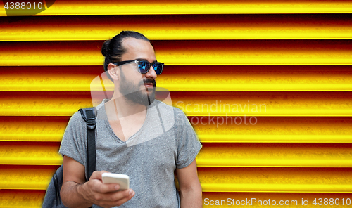 Image of man in sunglasses with smartphone and bag at wall