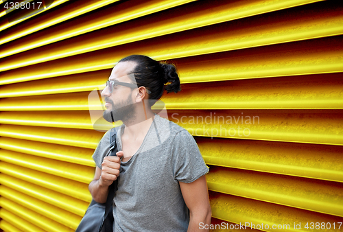 Image of man in sunglasses with bag standing at street wall