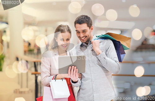 Image of couple with tablet pc and shopping bags in mall