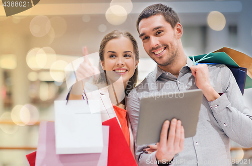 Image of couple with tablet pc and shopping bags in mall