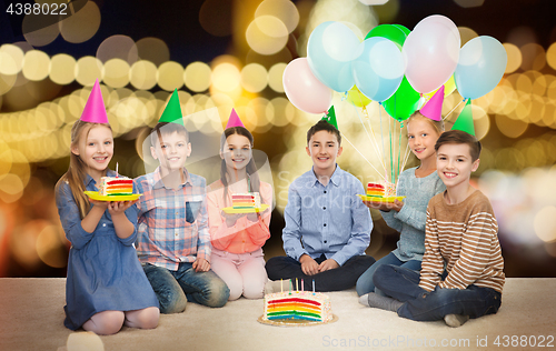 Image of happy children in party hats with birthday cake