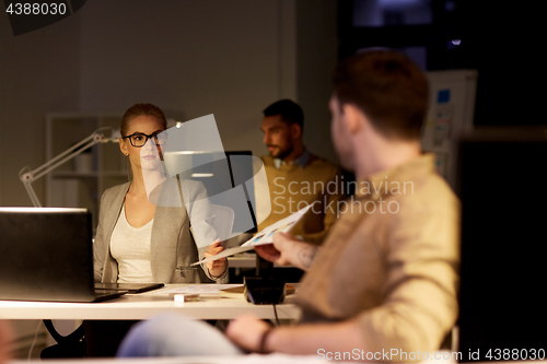 Image of coworkers with papers working late at office