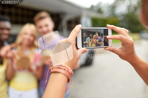 Image of woman photographing friends eating at food truck