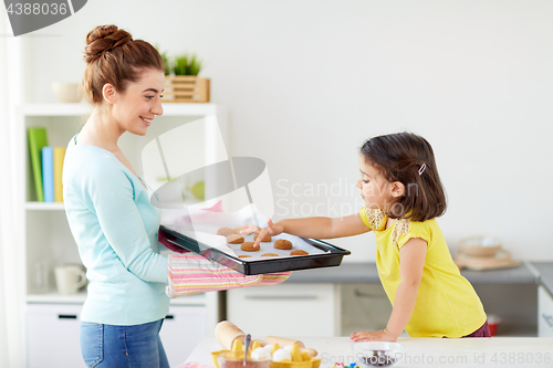 Image of happy mother and daughter baking cookies at home