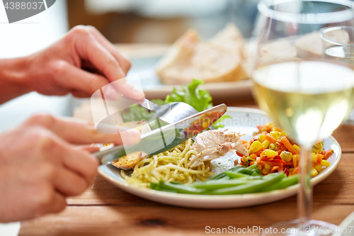 Image of hands of woman eating pasta with chicken meat