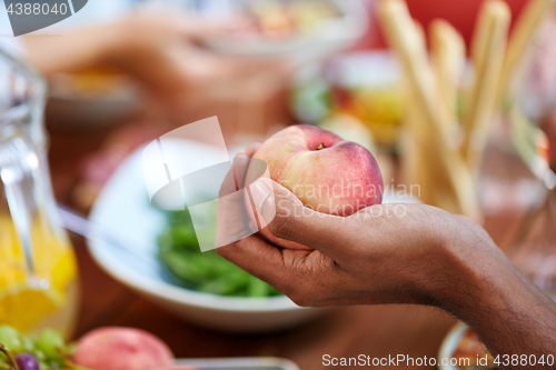 Image of male hand holding peach