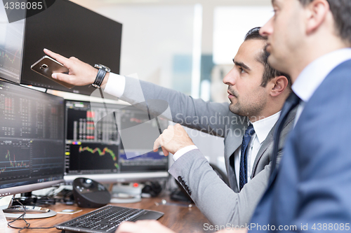 Image of Stock brokers looking at computer screens, trading online.