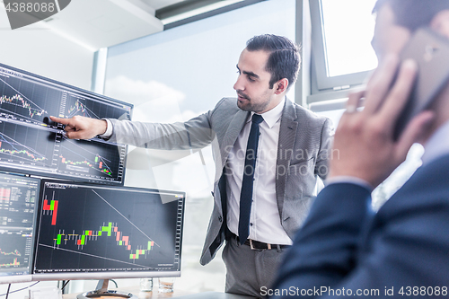 Image of Stock brokers looking at computer screens, trading online.