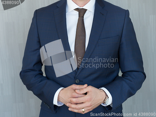 Image of Torso of a businessman standing with hands clenched in middle position in a classic navy blue suit.