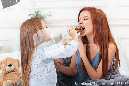 Image of A little cute girl enjoying, playing and creating with cake with mother