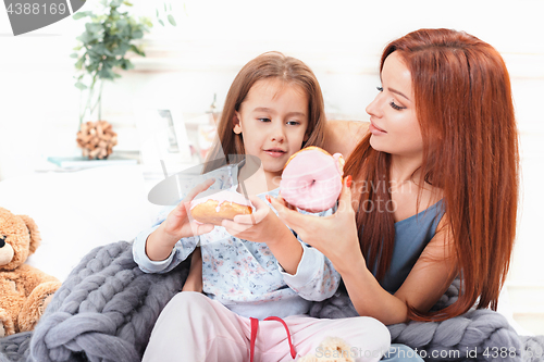 Image of A little cute girl enjoying, playing and creating with cake with mother