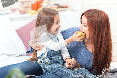 Image of A little cute girl enjoying, playing and creating with apple with mother