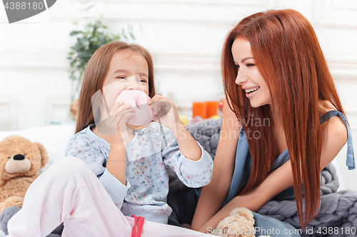 Image of A little cute girl enjoying, playing and creating with cake with mother