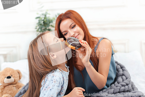 Image of A little cute girl enjoying, playing and creating with cake with mother