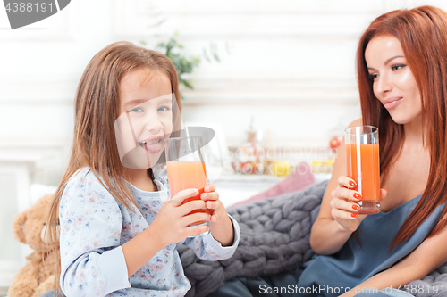 Image of A little cute girl enjoying, playing and creating with juice with mother