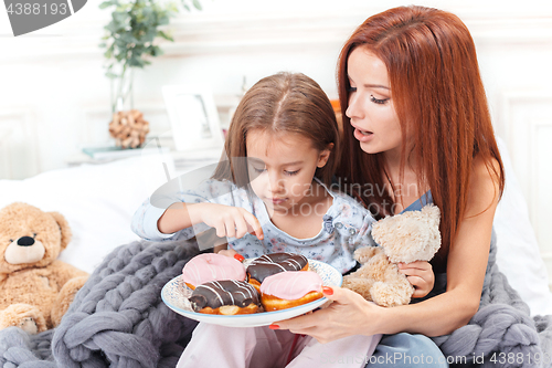 Image of A little cute girl enjoying, playing and creating with cake with mother