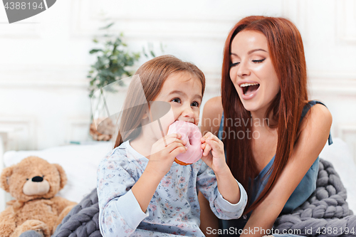 Image of A little cute girl enjoying, playing and creating with cake with mother