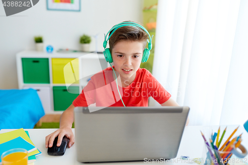 Image of boy in headphones playing video game on laptop