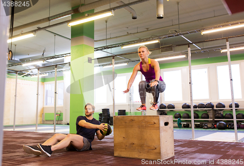 Image of woman and man with medicine ball exercising in gym