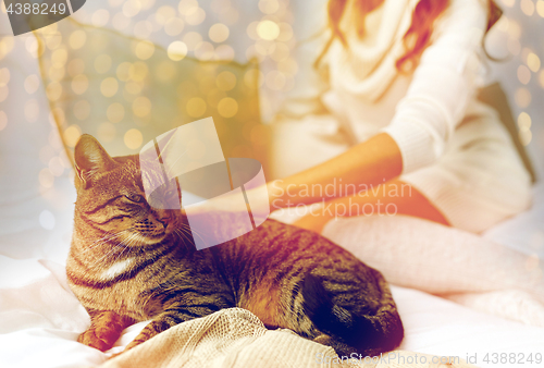 Image of young woman with cat lying in bed at home