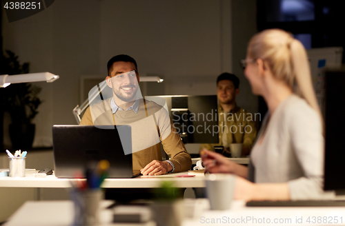 Image of coworkers with laptop working late at office