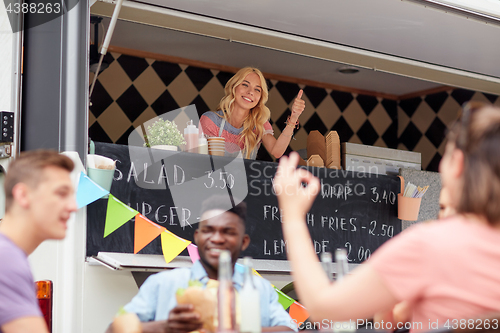 Image of happy saleswoman showing thumbs up at food truck