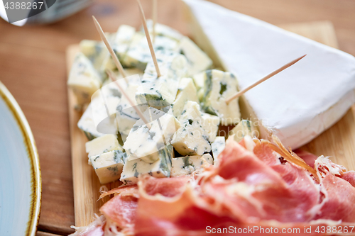 Image of blue cheese and jamon or parma ham on wooden board
