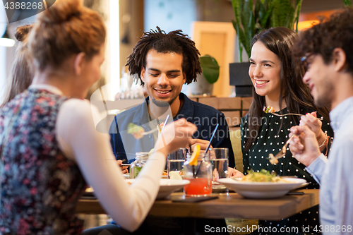 Image of happy friends eating at restaurant