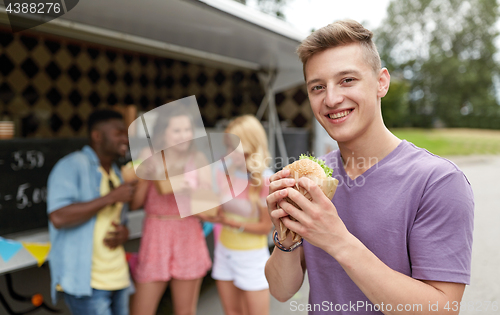 Image of happy man with hamburger and friends at food truck