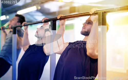 Image of group of young men doing pull-ups in gym