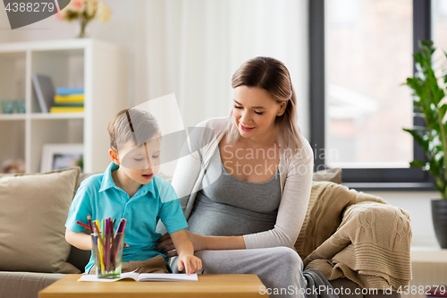 Image of pregnant mother and son with workbook at home