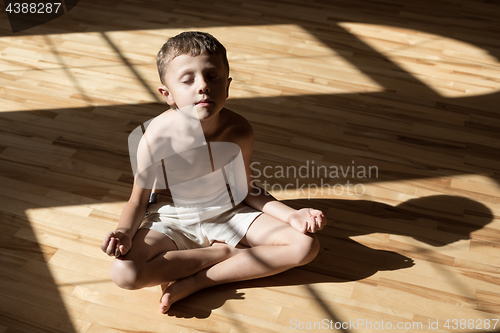 Image of Charming little boy is while doing yoga at home