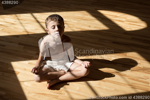 Image of Charming little boy is while doing yoga at home
