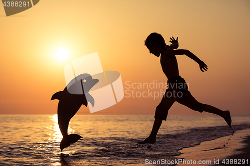 Image of One happy little boy playing on the beach at the sunset time.