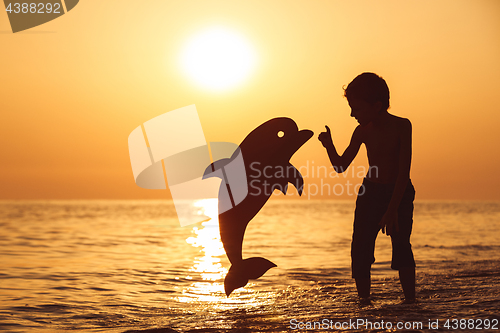 Image of One happy little boy playing on the beach at the sunset time.